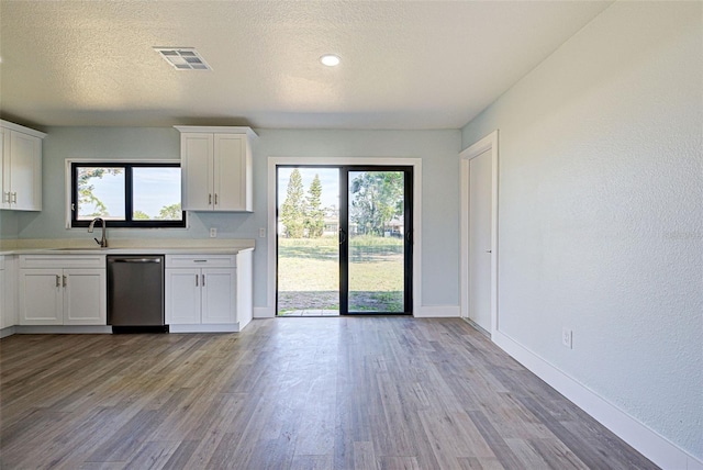 kitchen featuring visible vents, white cabinets, light wood-style flooring, light countertops, and stainless steel dishwasher