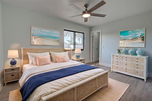 bedroom featuring ceiling fan, a textured ceiling, wood finished floors, and baseboards