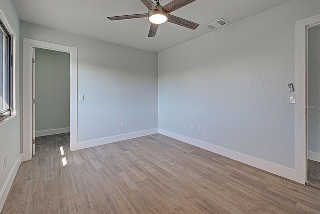 empty room with baseboards, visible vents, and light wood finished floors