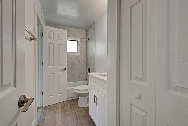 full bathroom featuring tiled shower / bath combo, vanity, hardwood / wood-style flooring, and toilet