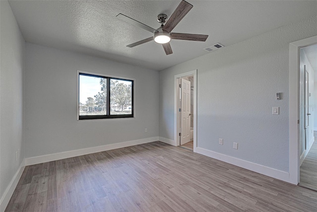 spare room with ceiling fan, light hardwood / wood-style flooring, and a textured ceiling