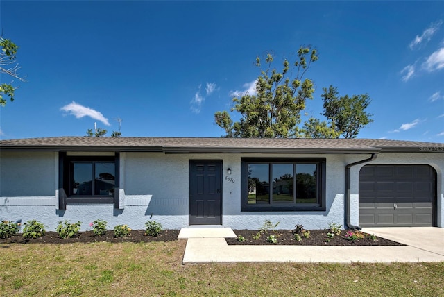 ranch-style house with a garage, concrete driveway, a front lawn, and stucco siding