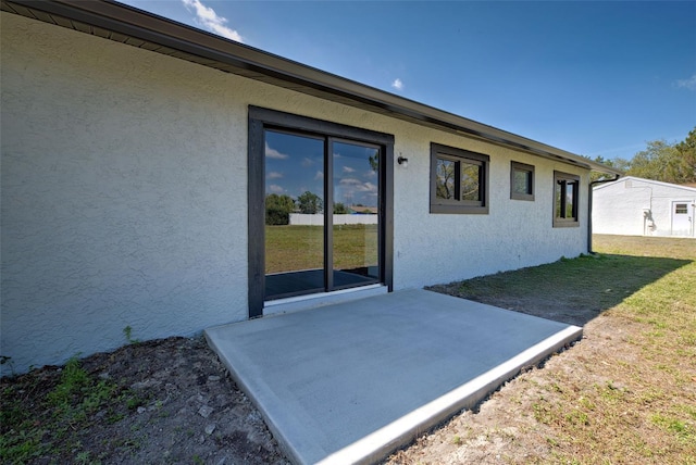 exterior space featuring a lawn, a patio area, and stucco siding