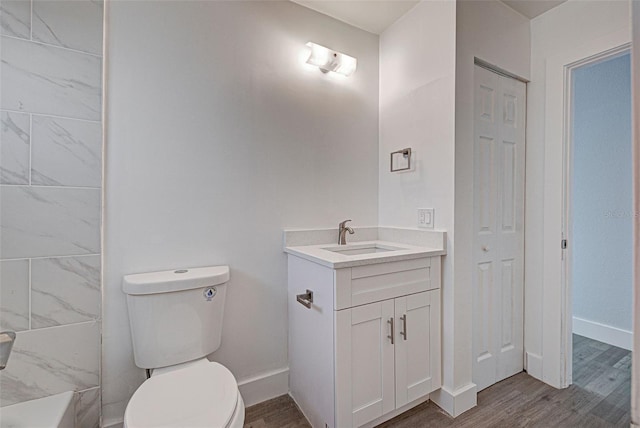 full bathroom with wood finished floors, vanity, toilet, and baseboards