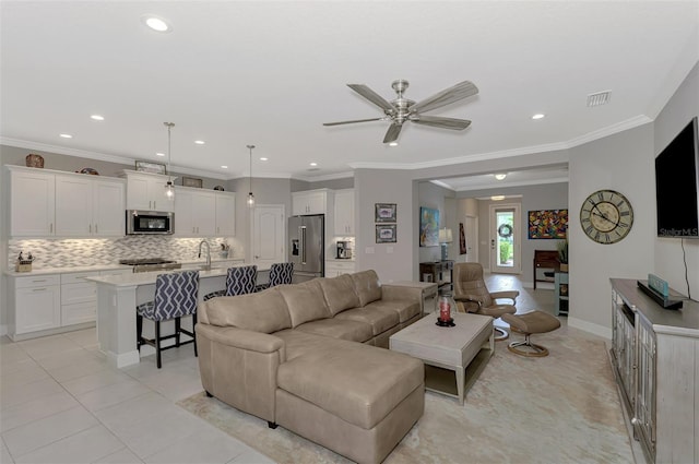 tiled living room with ornamental molding and ceiling fan