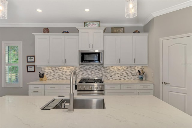 kitchen featuring sink, hanging light fixtures, stainless steel appliances, tasteful backsplash, and white cabinets