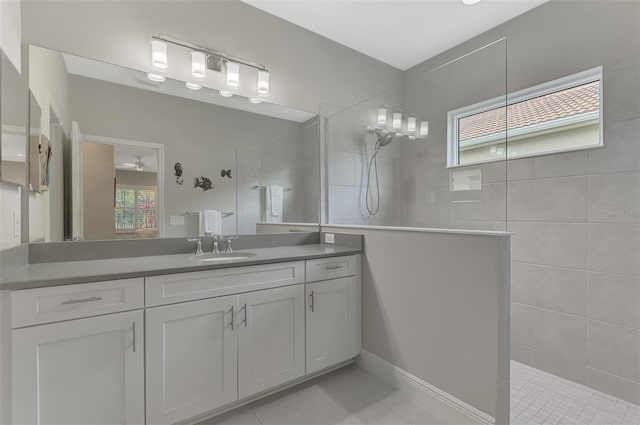 bathroom featuring vanity, a tile shower, tile patterned flooring, and a wealth of natural light