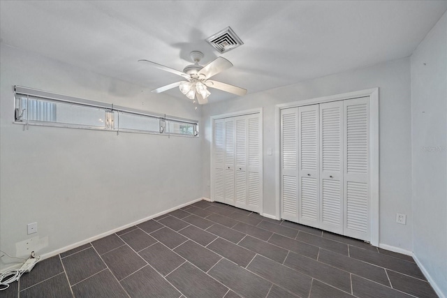 unfurnished bedroom featuring two closets and ceiling fan