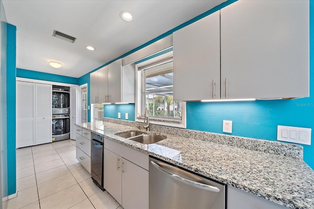 kitchen with white cabinetry, sink, light tile patterned floors, stainless steel appliances, and light stone countertops