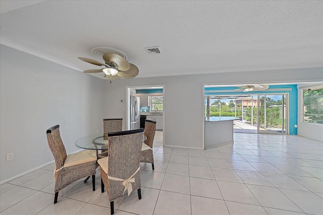 dining area featuring light tile patterned flooring, ceiling fan, sink, and a textured ceiling