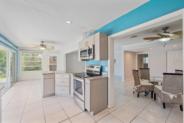 kitchen featuring light tile patterned floors, ceiling fan, light stone counters, stainless steel appliances, and a textured ceiling