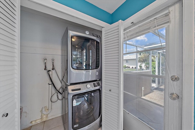 laundry room featuring stacked washer / drying machine and light tile patterned floors