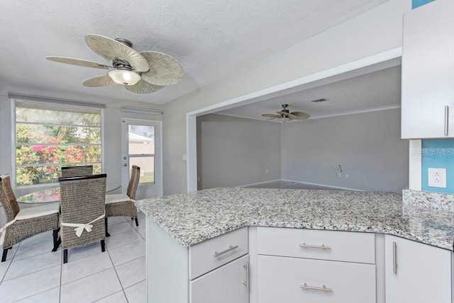 kitchen with white cabinetry, ceiling fan, kitchen peninsula, and light stone counters