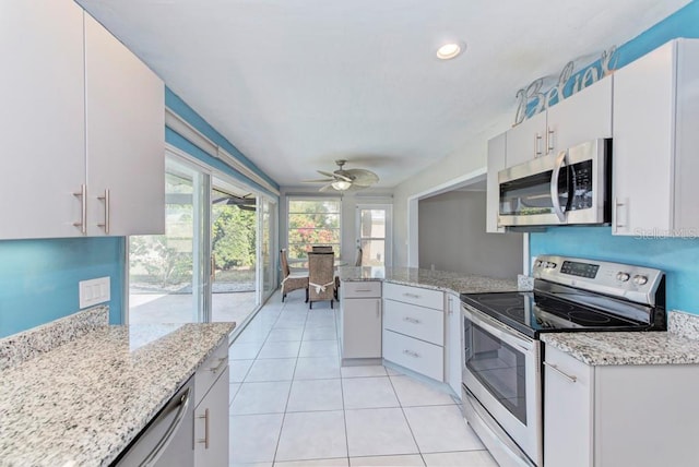 kitchen featuring light tile patterned flooring, appliances with stainless steel finishes, white cabinets, kitchen peninsula, and light stone countertops