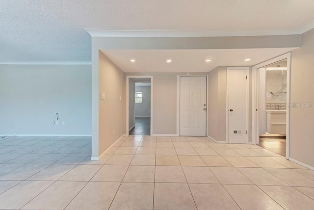 tiled spare room featuring ornamental molding and a textured ceiling