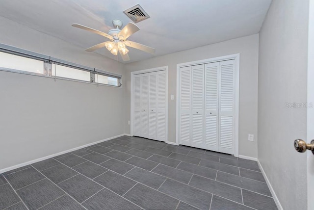 unfurnished bedroom featuring two closets and ceiling fan