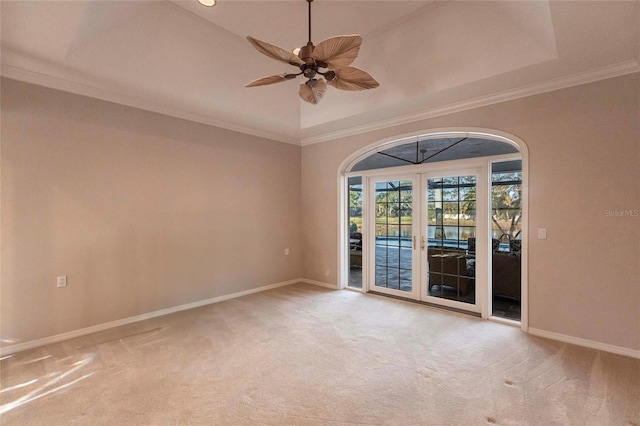 carpeted empty room with baseboards, a raised ceiling, ceiling fan, crown molding, and french doors