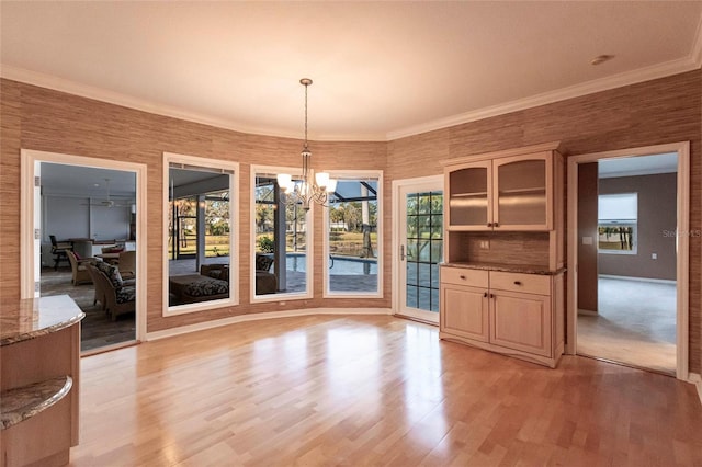 unfurnished dining area featuring a chandelier, crown molding, and light wood finished floors