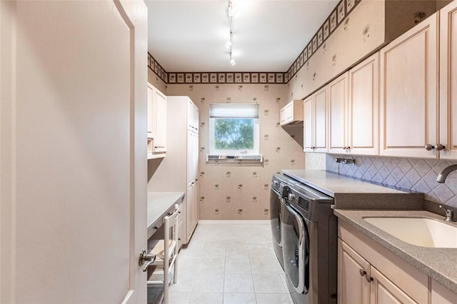 clothes washing area with a sink, baseboards, washer and dryer, cabinet space, and wallpapered walls