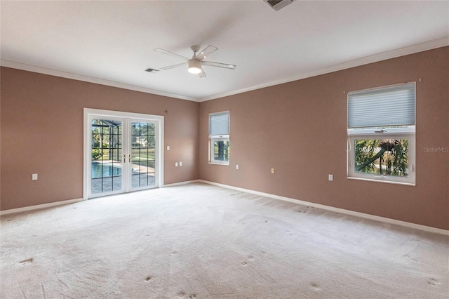 carpeted spare room featuring ornamental molding, french doors, ceiling fan, and baseboards