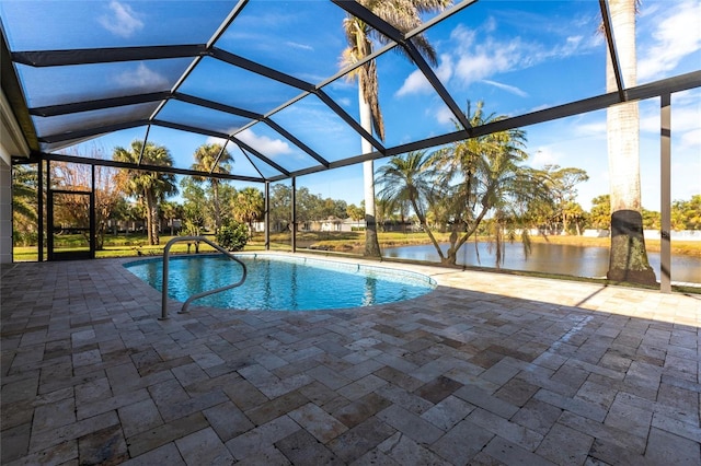 pool with glass enclosure, a patio area, and a water view