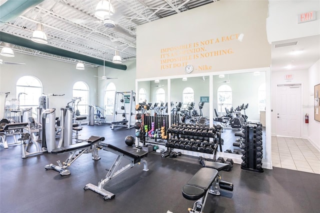 workout area featuring a towering ceiling, ceiling fan, and baseboards