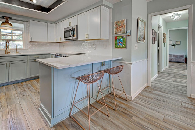 kitchen featuring sink, light hardwood / wood-style flooring, a breakfast bar area, stainless steel appliances, and kitchen peninsula