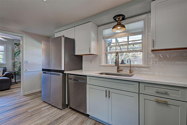 kitchen with pendant lighting, tasteful backsplash, sink, white cabinets, and stainless steel appliances