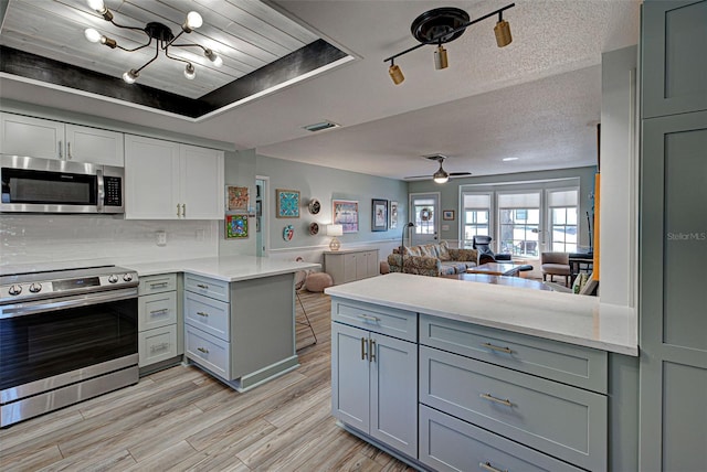 kitchen featuring ceiling fan, kitchen peninsula, stainless steel appliances, a textured ceiling, and light hardwood / wood-style flooring