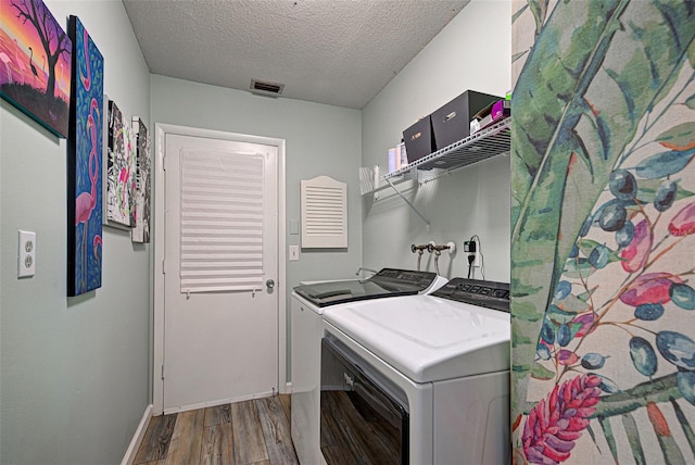 washroom featuring hardwood / wood-style flooring, washing machine and clothes dryer, and a textured ceiling