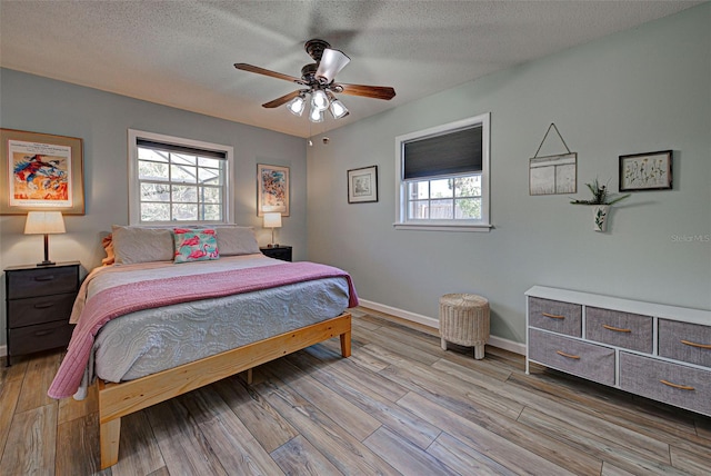 bedroom with ceiling fan, light hardwood / wood-style flooring, and a textured ceiling