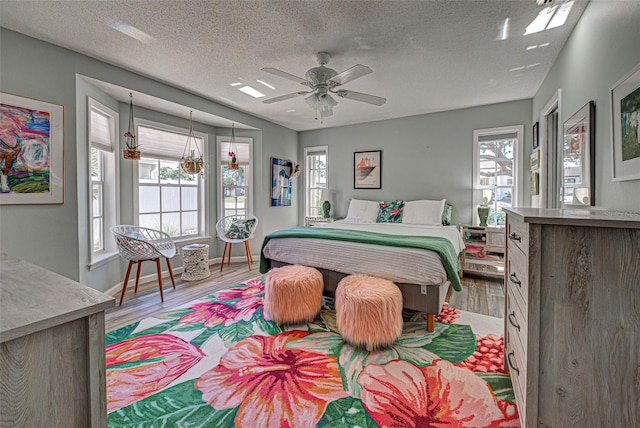 bedroom featuring hardwood / wood-style flooring, ceiling fan, and a textured ceiling