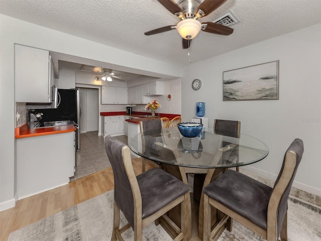 dining space featuring ceiling fan, light hardwood / wood-style floors, and a textured ceiling