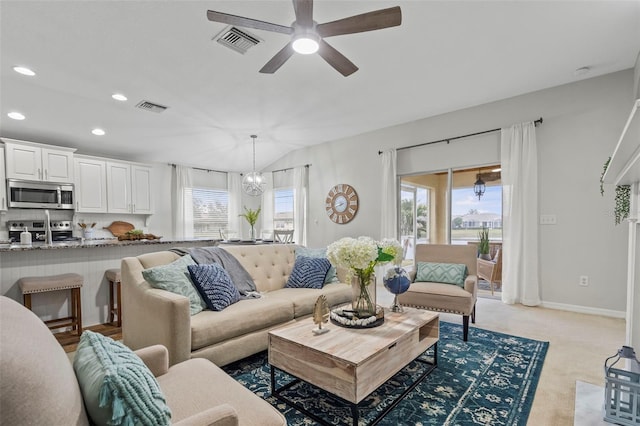 carpeted living room featuring ceiling fan with notable chandelier and a healthy amount of sunlight