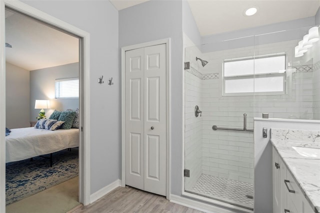 bathroom with hardwood / wood-style flooring, vanity, and a shower with door