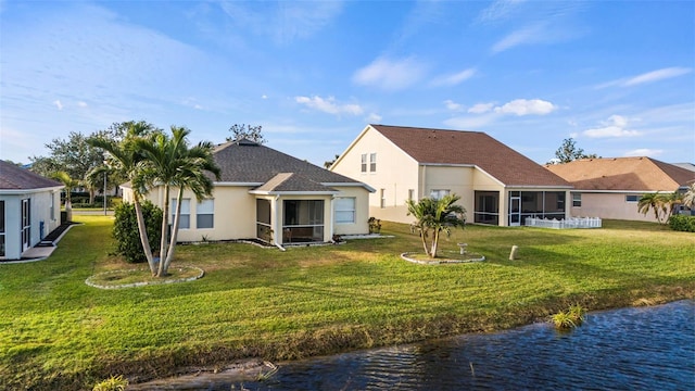 rear view of house with a yard, a sunroom, and a water view