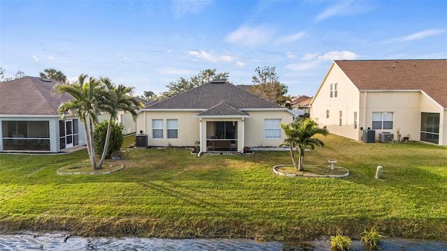 rear view of house with a sunroom, central AC unit, and a lawn