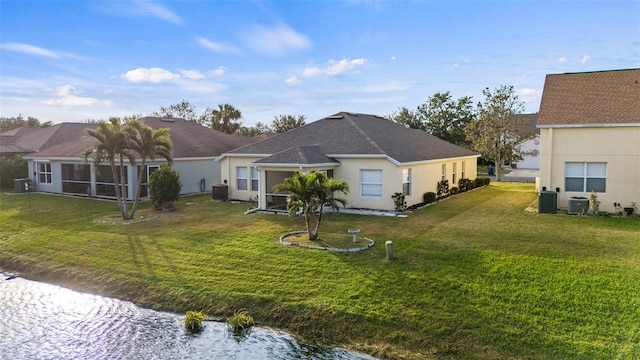 back of house with central AC, a water view, a sunroom, and a lawn