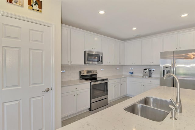 kitchen with white cabinetry, stainless steel appliances, and light stone counters