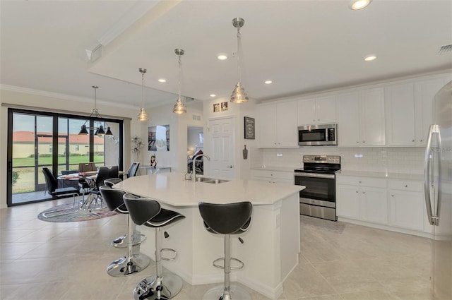 kitchen featuring pendant lighting, sink, appliances with stainless steel finishes, white cabinetry, and a kitchen island with sink