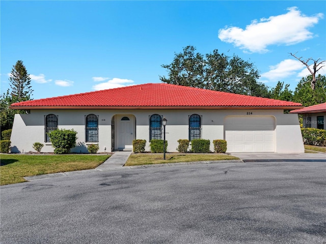 mediterranean / spanish-style home with a garage and a front lawn