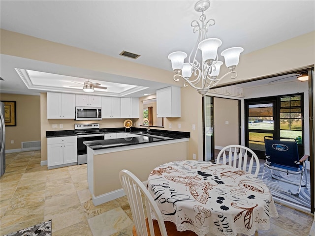 dining area featuring sink, a raised ceiling, and ceiling fan with notable chandelier