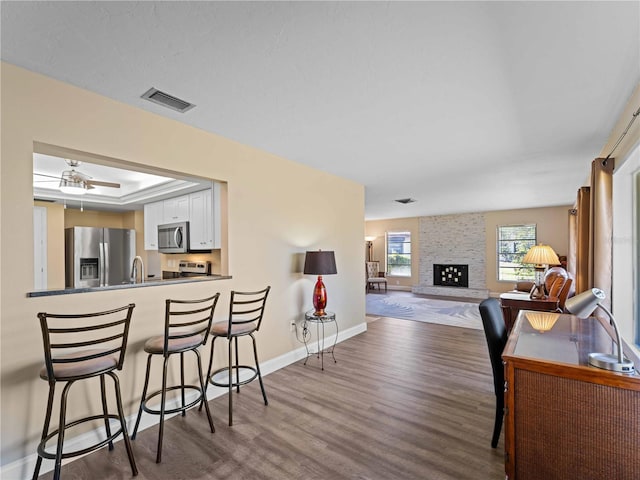 interior space with dark wood-type flooring, ceiling fan, a fireplace, and sink