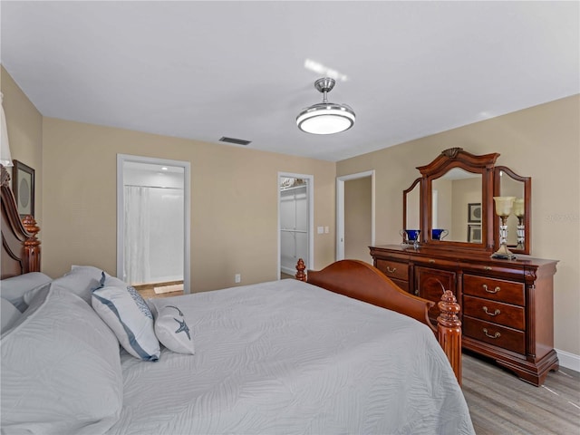 bedroom with a spacious closet, light wood-type flooring, and a closet