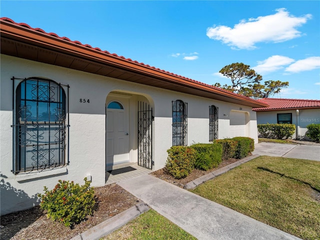 view of exterior entry featuring a garage and a lawn