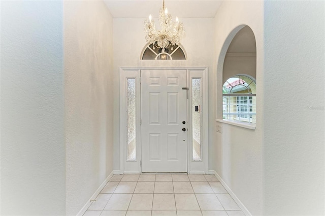 tiled foyer entrance featuring an inviting chandelier