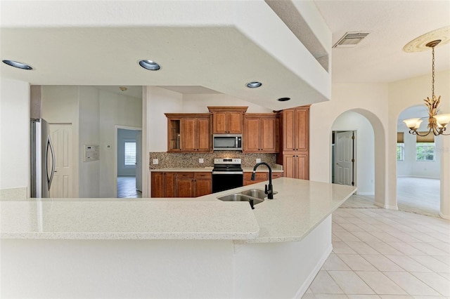 kitchen with sink, tasteful backsplash, an inviting chandelier, hanging light fixtures, and stainless steel appliances