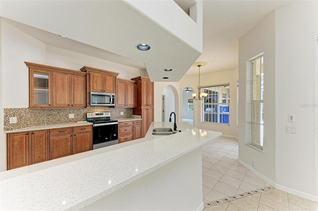 kitchen with appliances with stainless steel finishes, a wealth of natural light, tasteful backsplash, sink, and light tile patterned floors