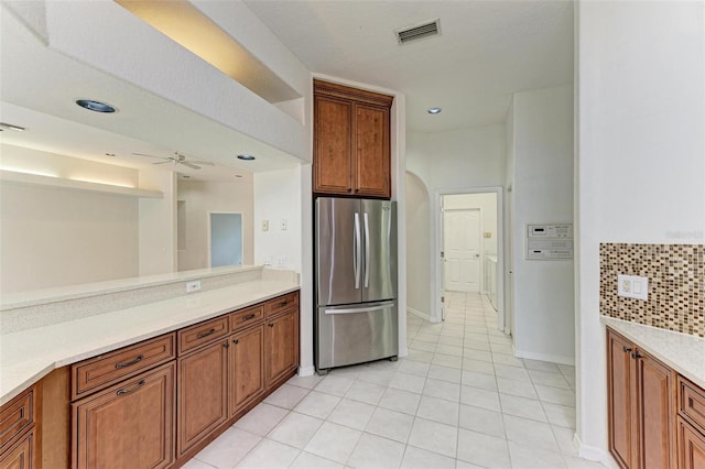 kitchen featuring stainless steel refrigerator, ceiling fan, light tile patterned floors, and backsplash