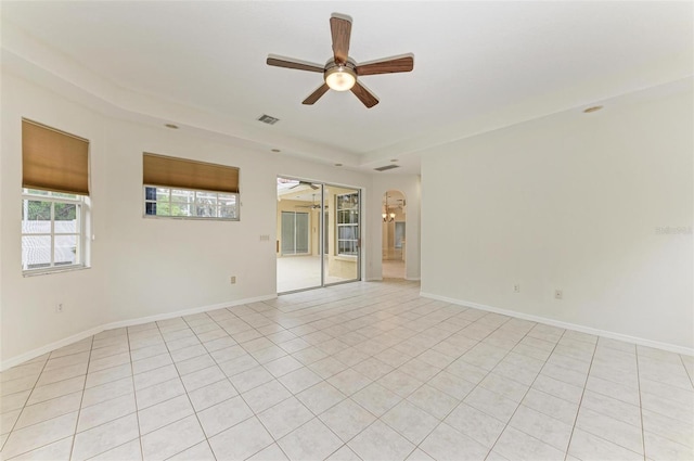 spare room featuring a raised ceiling, light tile patterned floors, and ceiling fan